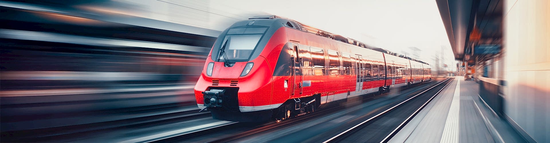 Ein roter Regionalzug fährt durch einen Bahnhof