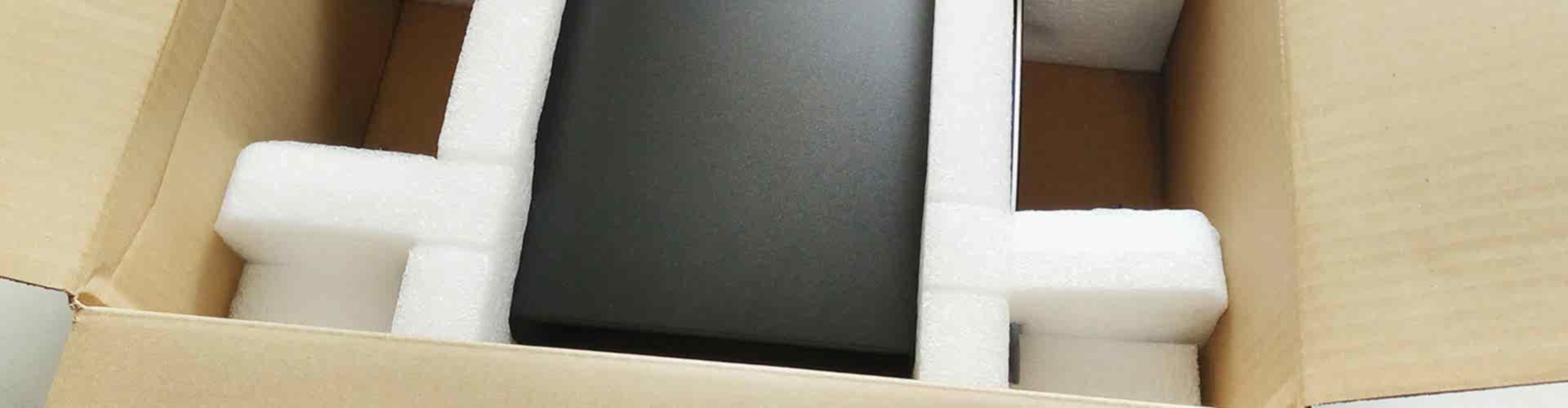schwarzes Gerät von weißem Verpackungsschaum in einem Karton gesichert